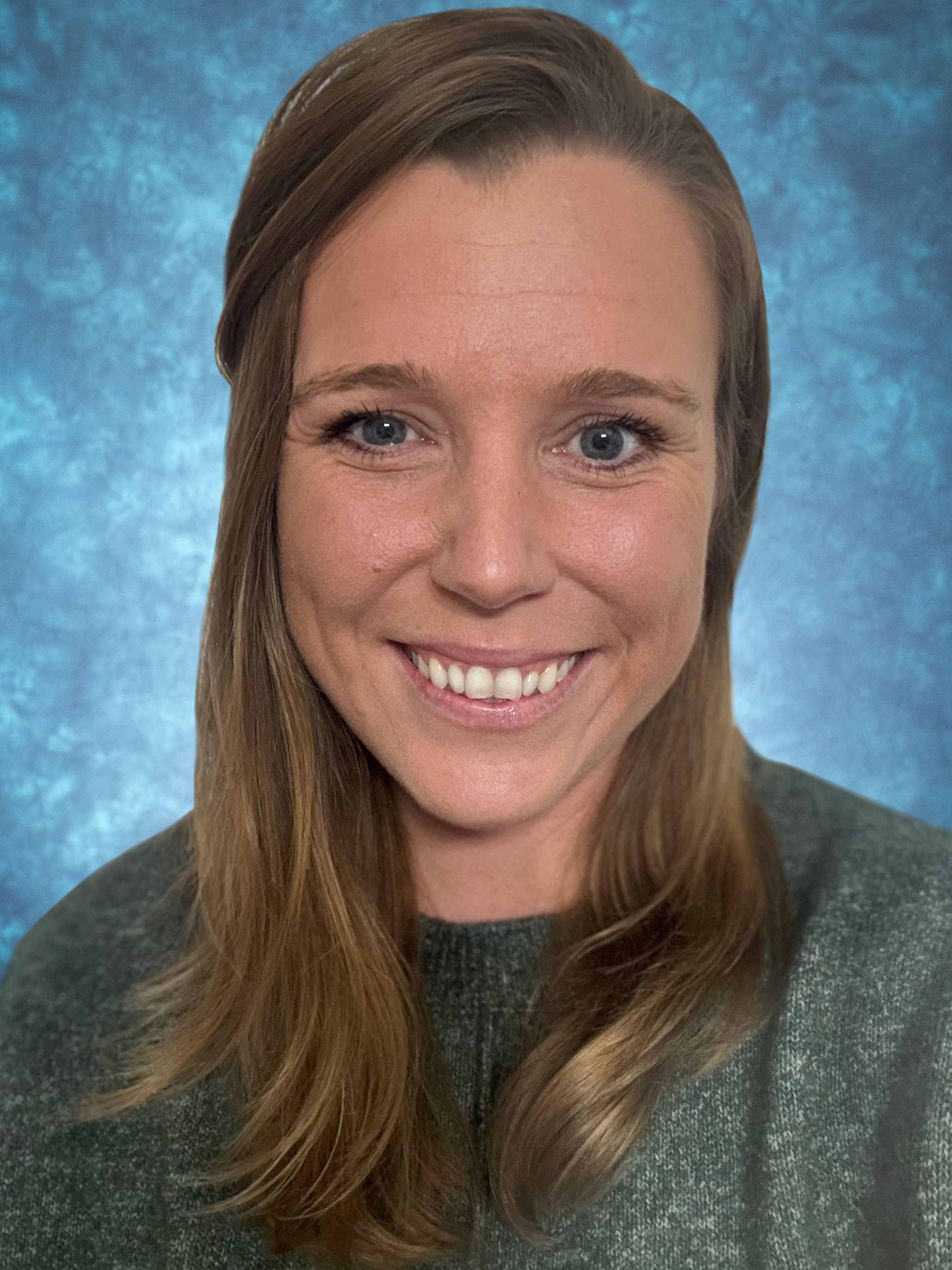Portrait of a smiling woman with long hair, wearing a green sweater, set against a blue textured background.